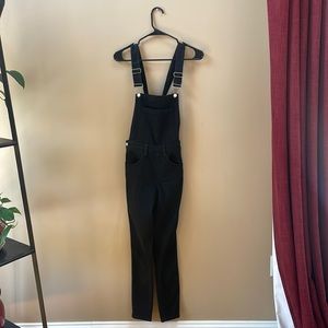 Black denim overalls, skinny leg, form fitting, zip and button straps
